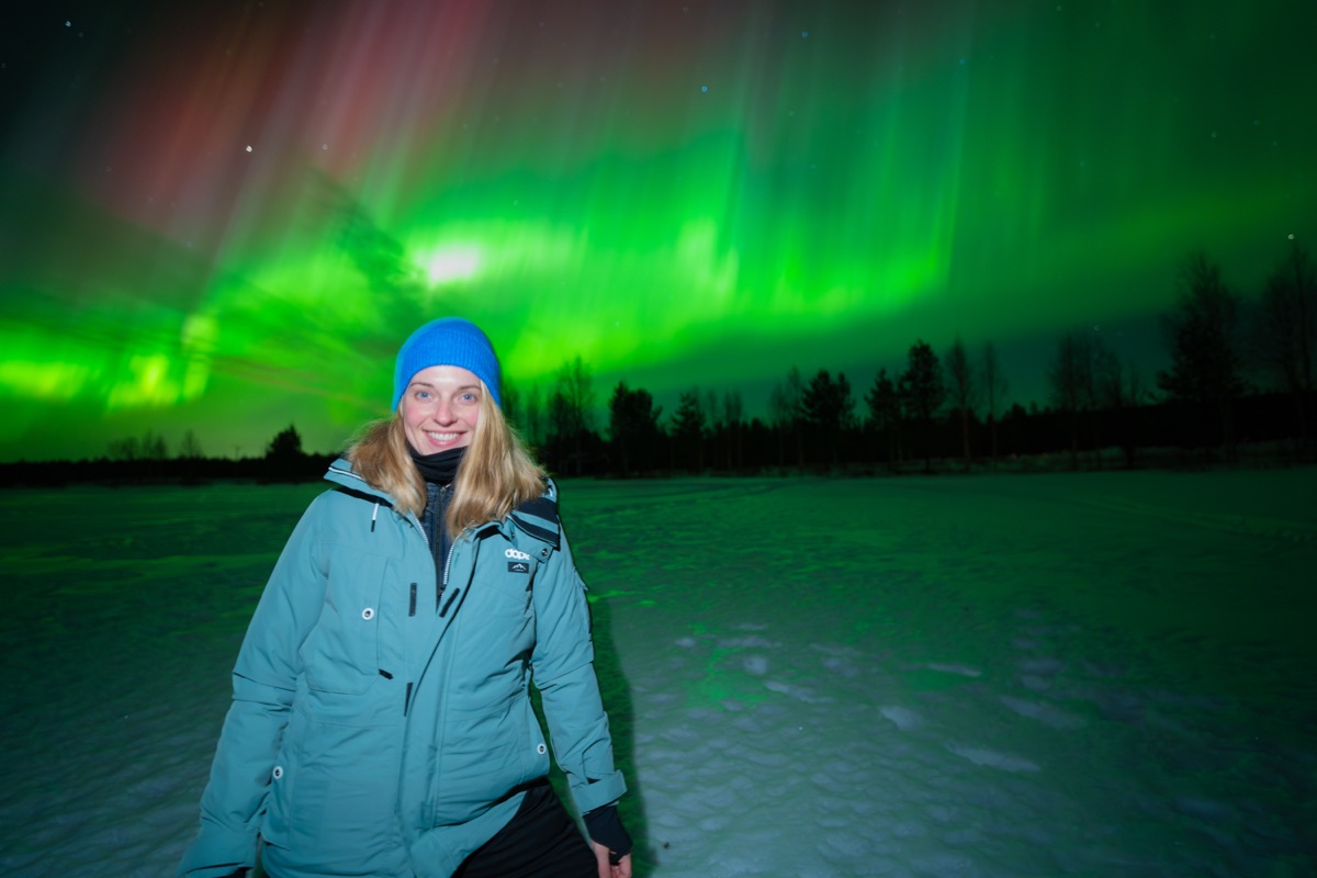 Guest in a blue jacket beneath green and pink aurora