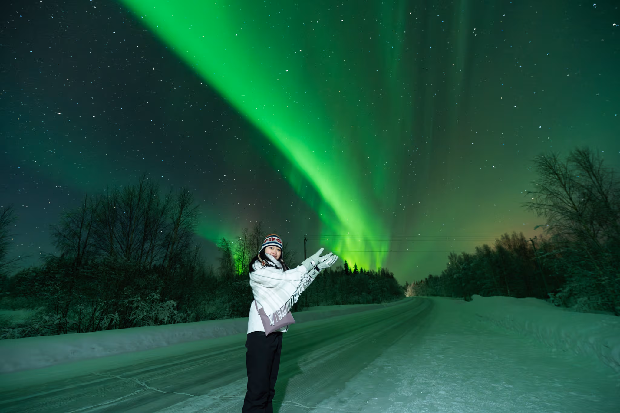 A man pointing at the aurora across a snowfield