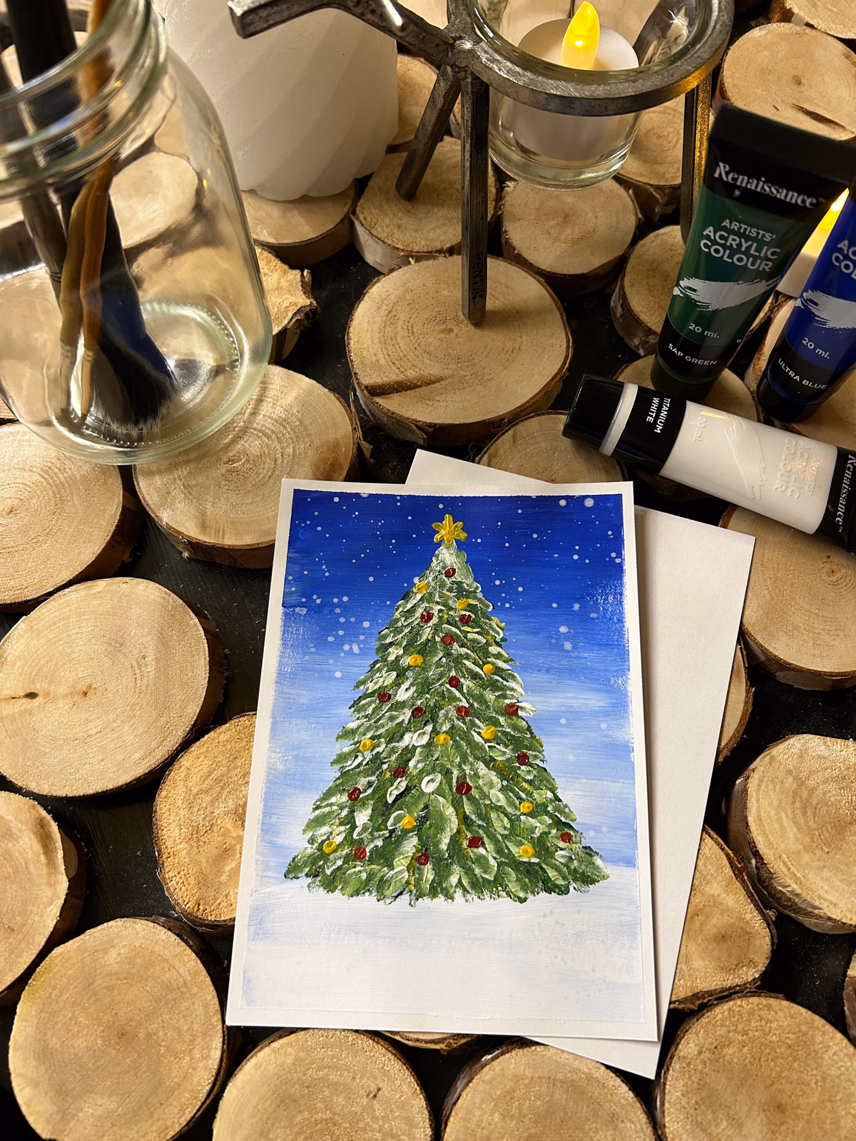 Finished Christmas tree postcard beside painting supplies